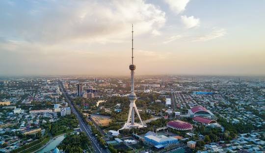 The futuristic Tashkent TV Tower rising above the modern city skyline and parks in Uzbekistan